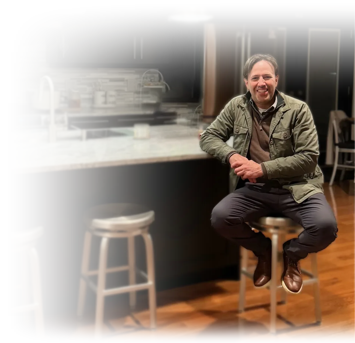 Mike Spina, founder of Spina, LLC, seated at a kitchen counter with an open seat beside him